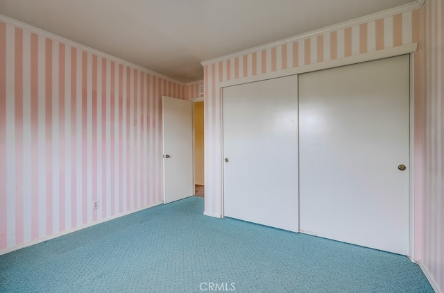 unfurnished bedroom featuring crown molding, carpet flooring, and a closet