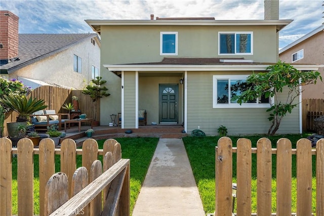 traditional-style house featuring a chimney, fence private yard, stucco siding, and a front yard