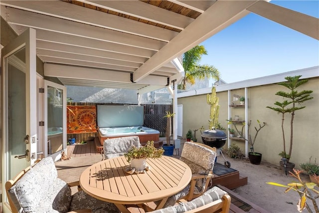 view of patio featuring outdoor dining area, a hot tub, and fence