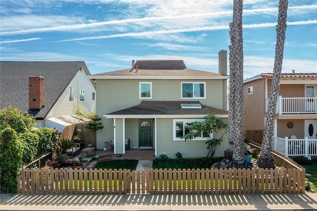 american foursquare style home with a porch, a fenced front yard, and stucco siding