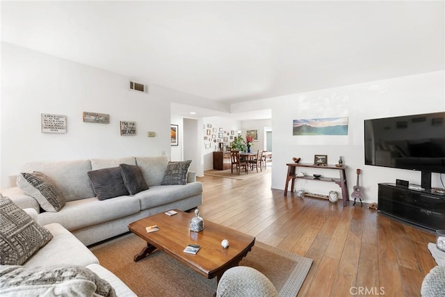 living room with hardwood / wood-style floors and visible vents