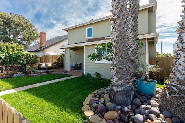 rear view of property with fence, a lawn, and a patio area