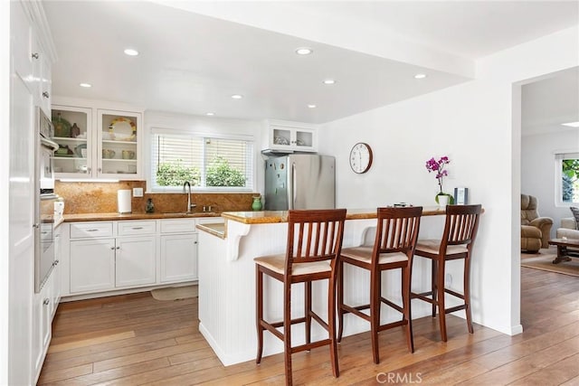 kitchen featuring freestanding refrigerator, a sink, light wood finished floors, and a wealth of natural light