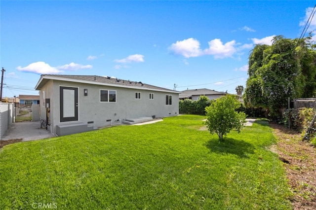 back of property featuring a fenced backyard, a gate, stucco siding, and a yard