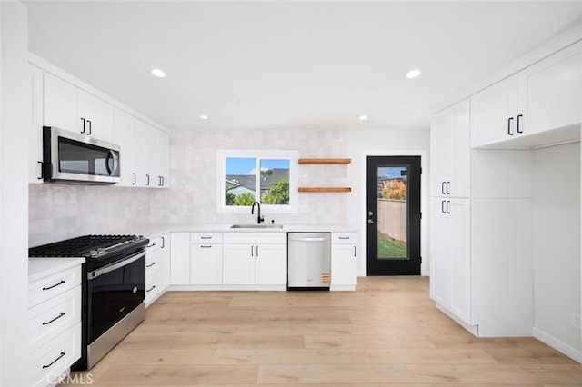 kitchen with light countertops, stainless steel appliances, a sink, and tasteful backsplash