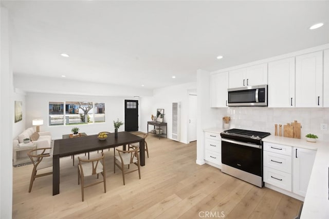 kitchen with decorative backsplash, stove, recessed lighting, light countertops, and stainless steel microwave