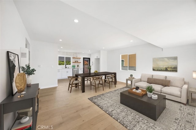 living area with recessed lighting, baseboards, and light wood-style flooring