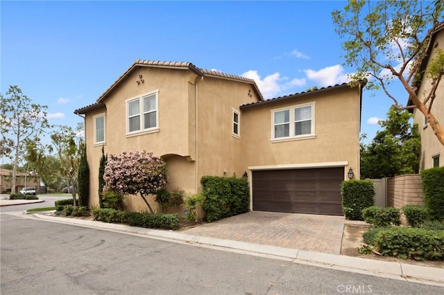 view of front of property with a garage, fence, stucco siding, and decorative driveway
