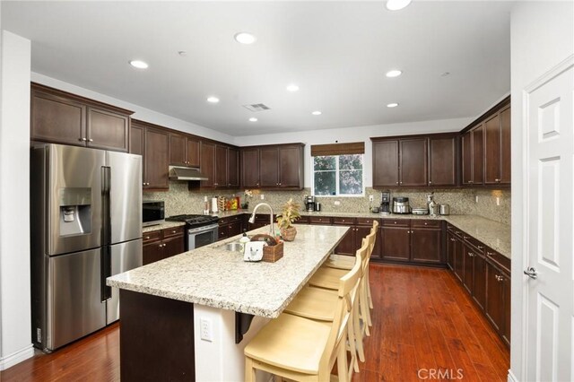 kitchen featuring a sink, dark brown cabinetry, stainless steel appliances, and under cabinet range hood