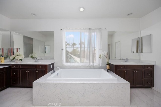 full bathroom with a sink, a garden tub, and two vanities