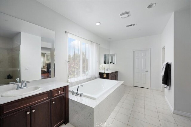 bathroom with a sink, tile patterned floors, two vanities, visible vents, and a garden tub