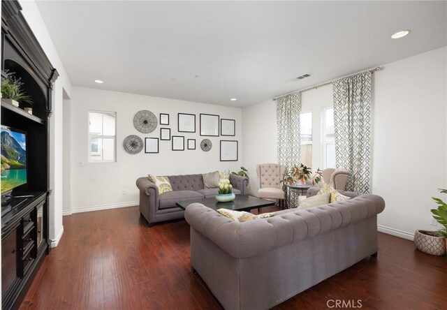 living area with visible vents, plenty of natural light, and dark wood finished floors