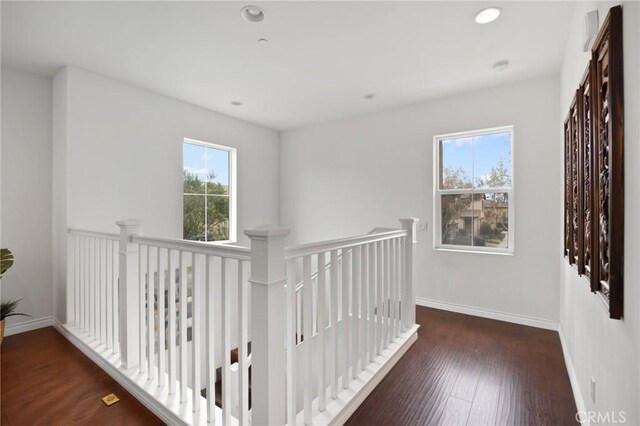 hall with baseboards, recessed lighting, wood finished floors, and an upstairs landing