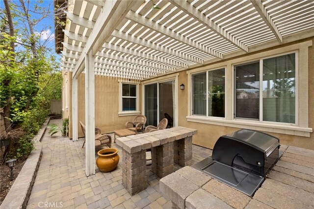 view of patio featuring a pergola, fence, grilling area, and an outdoor kitchen