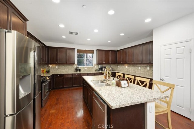 kitchen with dark brown cabinetry, appliances with stainless steel finishes, a sink, dark wood-type flooring, and visible vents
