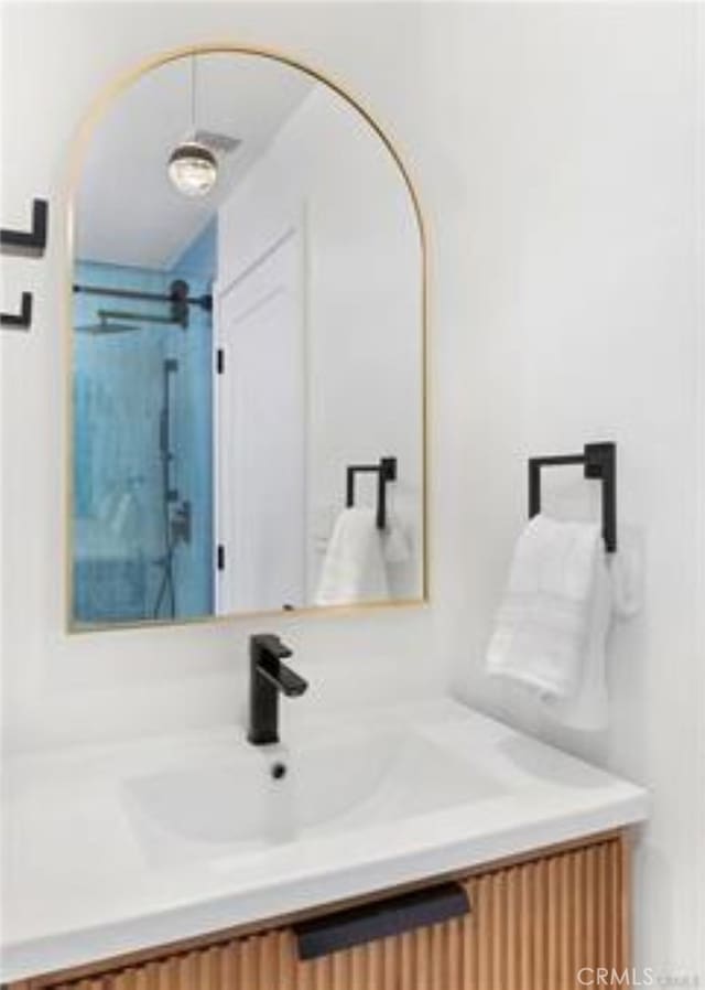 bathroom featuring a shower and vanity