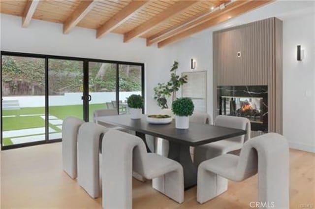 dining room featuring a multi sided fireplace, wood ceiling, and beam ceiling