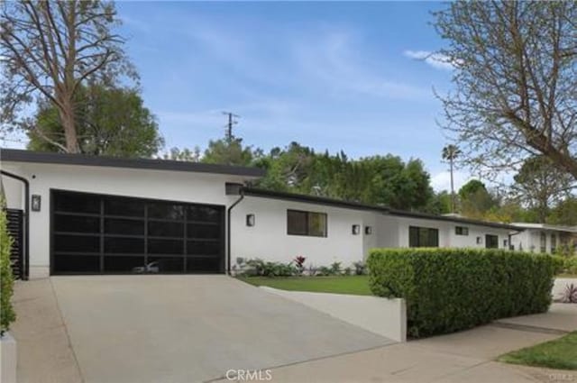 view of front of house with an attached garage, driveway, and stucco siding