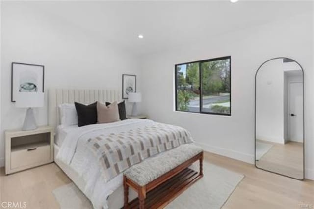 bedroom with baseboards, arched walkways, light wood-style flooring, and recessed lighting