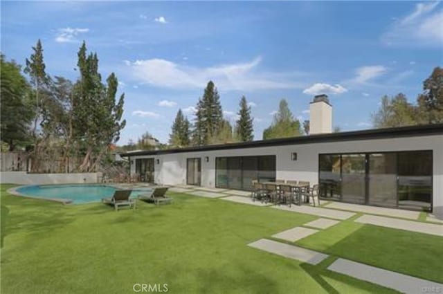 back of property with a fenced in pool, a patio area, and a yard