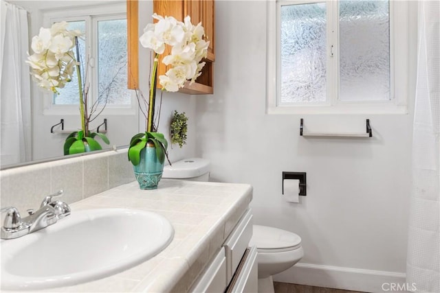 bathroom with vanity, baseboards, and toilet