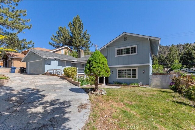 view of front of home with fence, driveway, a front lawn, and a garage