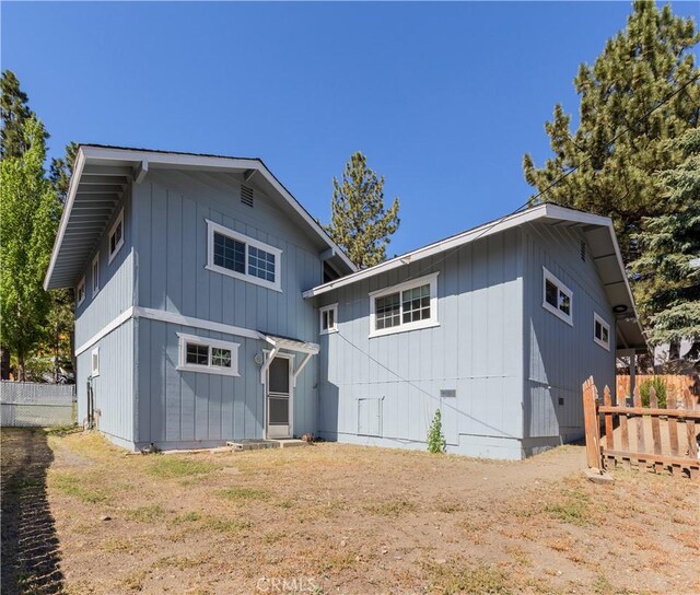 rear view of house featuring fence and board and batten siding
