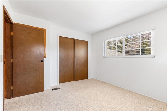 unfurnished bedroom featuring visible vents, carpet, and a closet