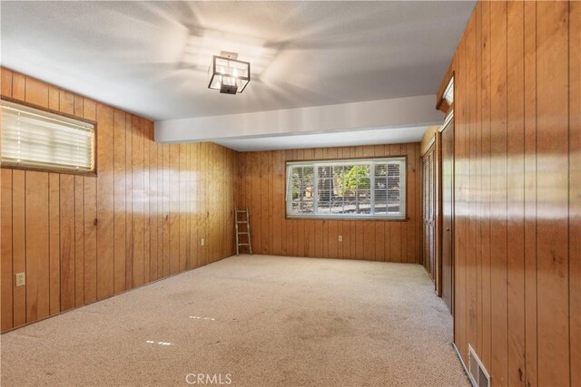 unfurnished room with visible vents, carpet, and wooden walls
