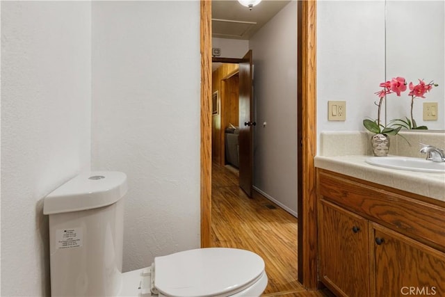 half bathroom with toilet, wood finished floors, and vanity