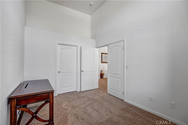 carpeted bedroom featuring baseboards and a towering ceiling