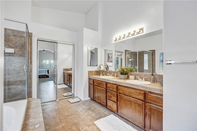 ensuite bathroom featuring a sink, tile patterned flooring, a stall shower, and double vanity