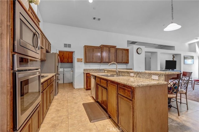 kitchen featuring visible vents, a breakfast bar, a sink, appliances with stainless steel finishes, and light tile patterned floors