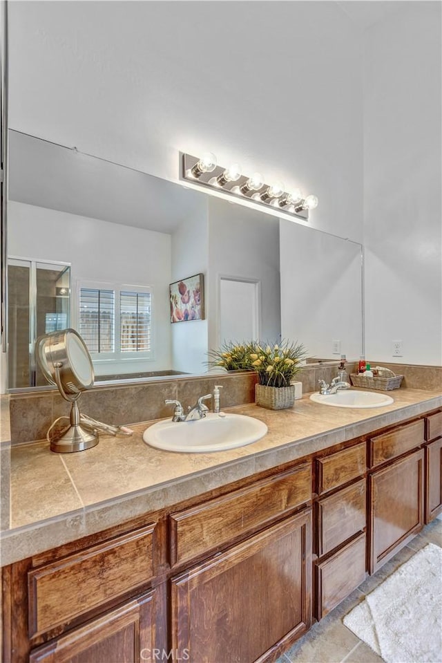 full bath featuring double vanity, a sink, and a stall shower