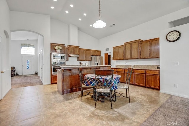 kitchen with appliances with stainless steel finishes, light countertops, arched walkways, high vaulted ceiling, and visible vents