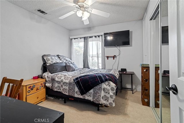 bedroom featuring carpet floors, ceiling fan, a textured ceiling, and visible vents