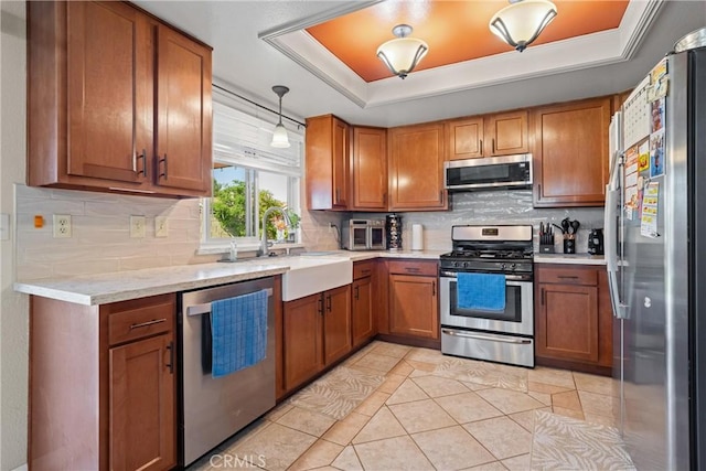 kitchen featuring brown cabinetry, backsplash, a tray ceiling, and stainless steel appliances