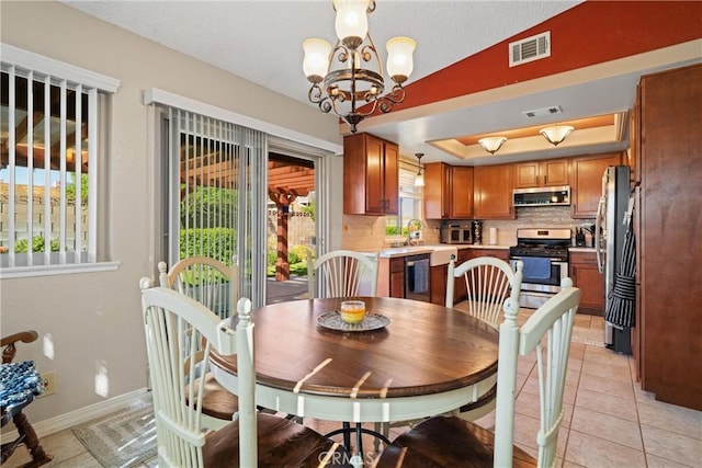 dining room featuring visible vents, a tray ceiling, a chandelier, and light tile patterned flooring