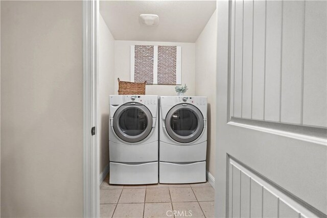 laundry room featuring separate washer and dryer, laundry area, light tile patterned floors, and baseboards
