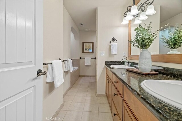 full bath with tile patterned flooring, a sink, double vanity, and an inviting chandelier