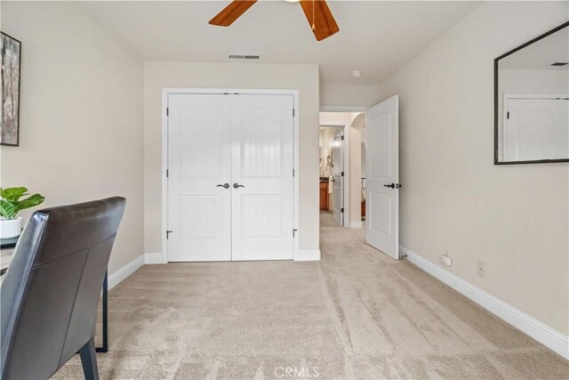 unfurnished office with baseboards, a ceiling fan, light colored carpet, and visible vents