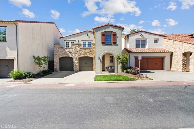 mediterranean / spanish house featuring concrete driveway, a garage, a tile roof, and stucco siding