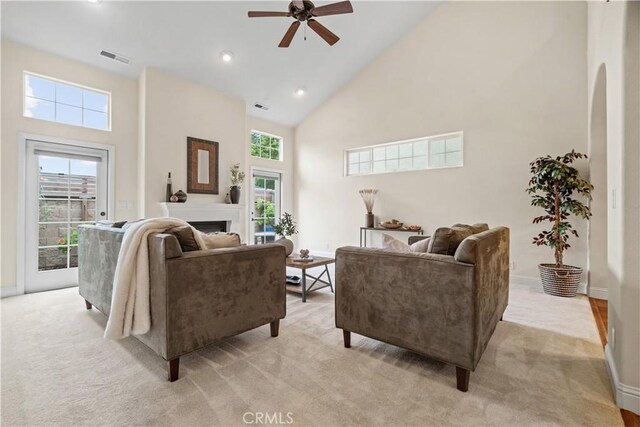 living room with light carpet, a fireplace, high vaulted ceiling, a ceiling fan, and visible vents