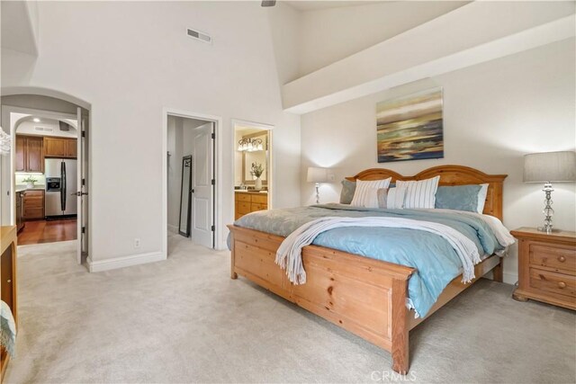 bedroom featuring light colored carpet, a high ceiling, visible vents, and stainless steel fridge