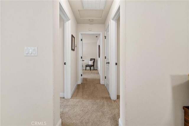 hall featuring baseboards, light carpet, and visible vents