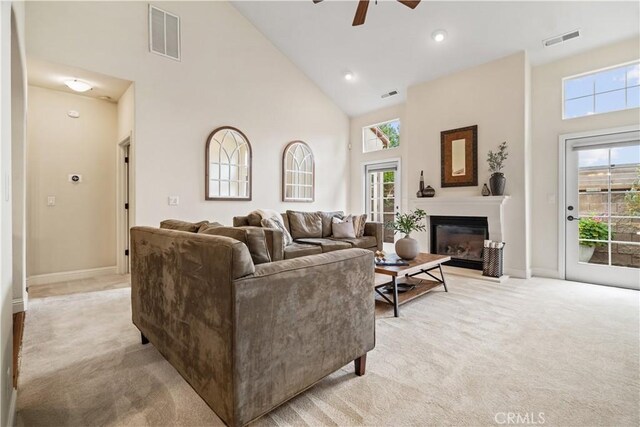 living room featuring high vaulted ceiling, visible vents, a ceiling fan, and light colored carpet