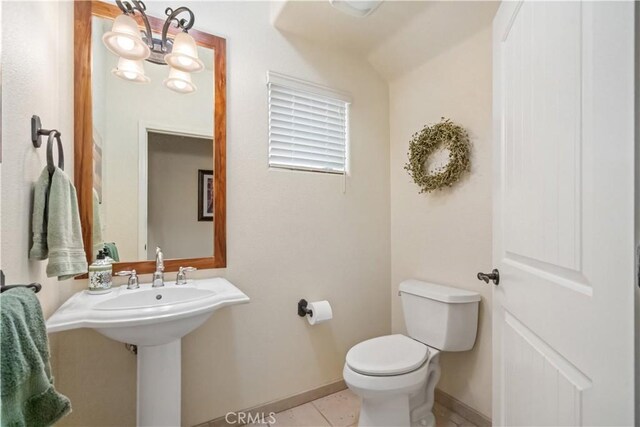 bathroom with toilet, baseboards, a chandelier, and tile patterned floors