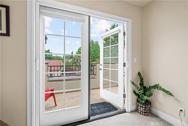 doorway with baseboards and carpet