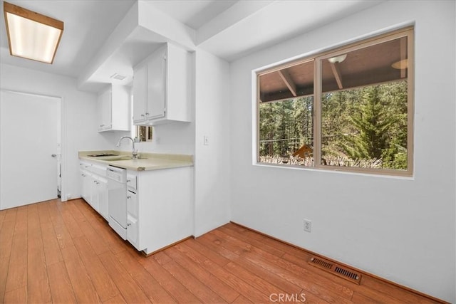 kitchen featuring visible vents, light countertops, white cabinetry, a sink, and dishwasher