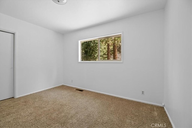 carpeted spare room featuring baseboards and visible vents